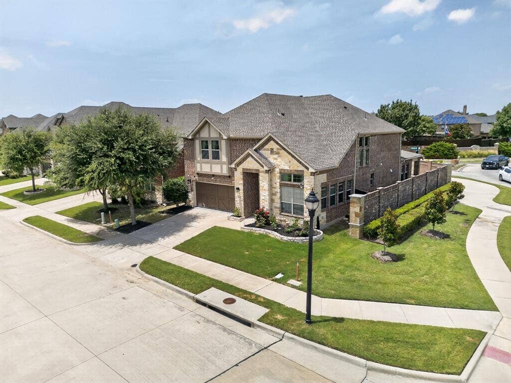 702 Callaway Drive, Allen, TX 75013 Brick and stone exterior featuring multiple gables, an attached two-car garage, and a manicured lawn