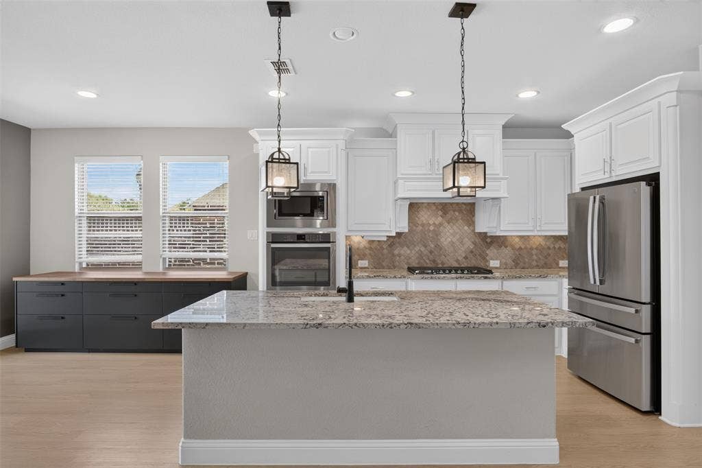 702 Callaway Drive, Allen, TX 75013 Kitchen featuring white cabinetry, a stone-finish island with pendant lighting, stainless steel appliances, and wood-finish flooring
