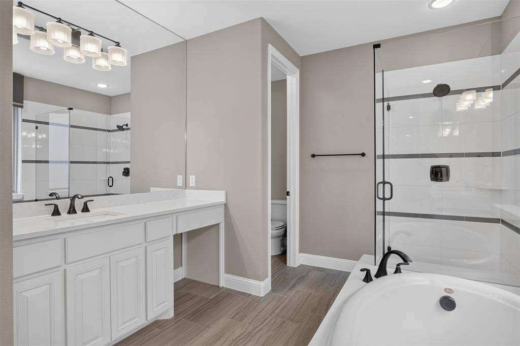 702 Callaway Drive, Allen, TX 75013 Expansive vanity with a white countertop and dual sinks, complemented by a large wall-mounted mirror and contemporary light fixture