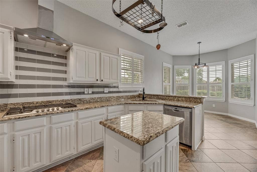 Kitchen featuring white cabinetry, granite countertops, stainless steel appliances, a tile backsplash, and a bay window with plantation shutters