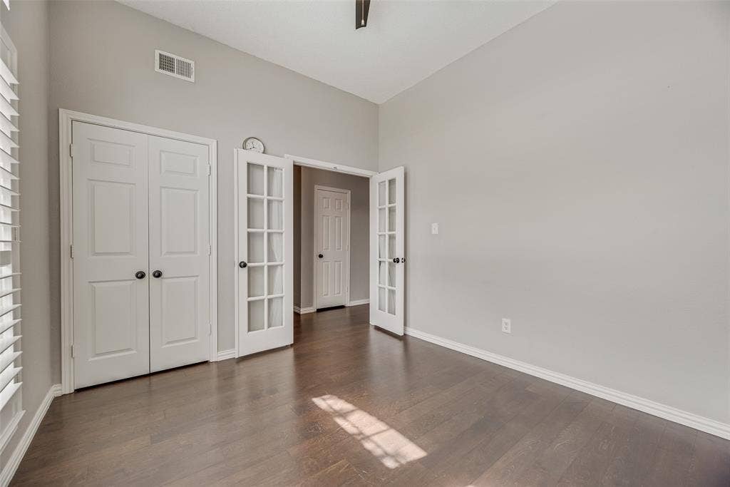 Vaulted ceiling, dark wood-finish flooring, white panel bi-fold doors, white French doors, and plantation shutters
