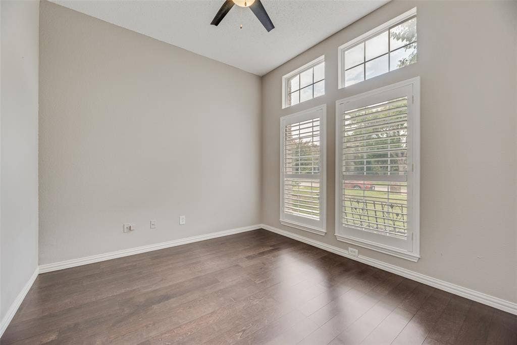 Wood-finish flooring, high ceilings, large windows with plantation shutters, and a ceiling fan