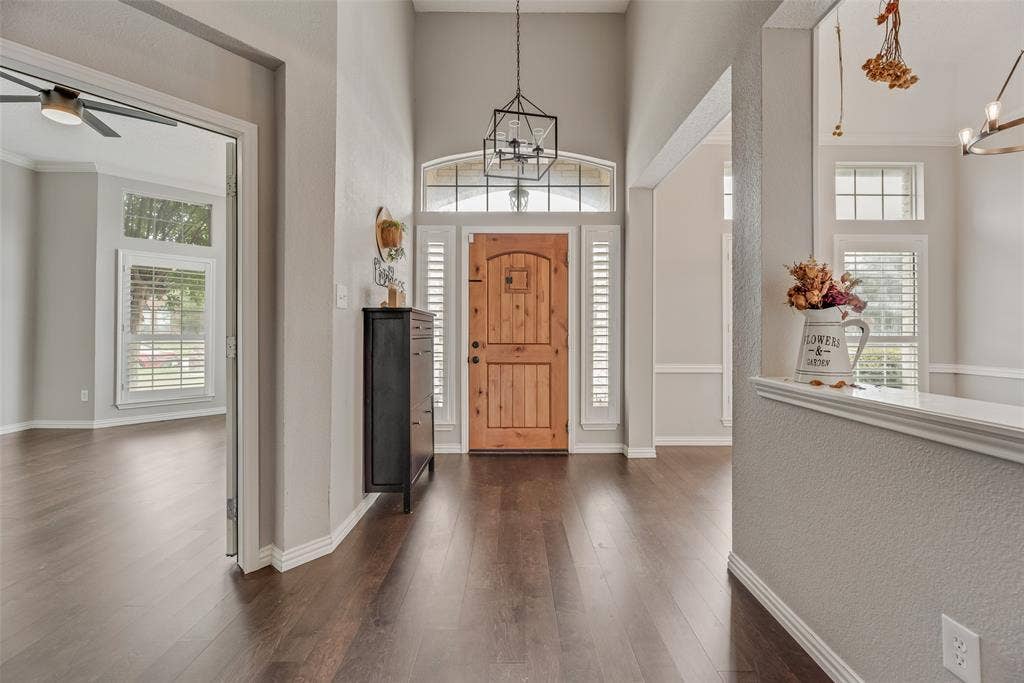 Vaulted entryway featuring a wood front door, transom window, and wood-finish flooring