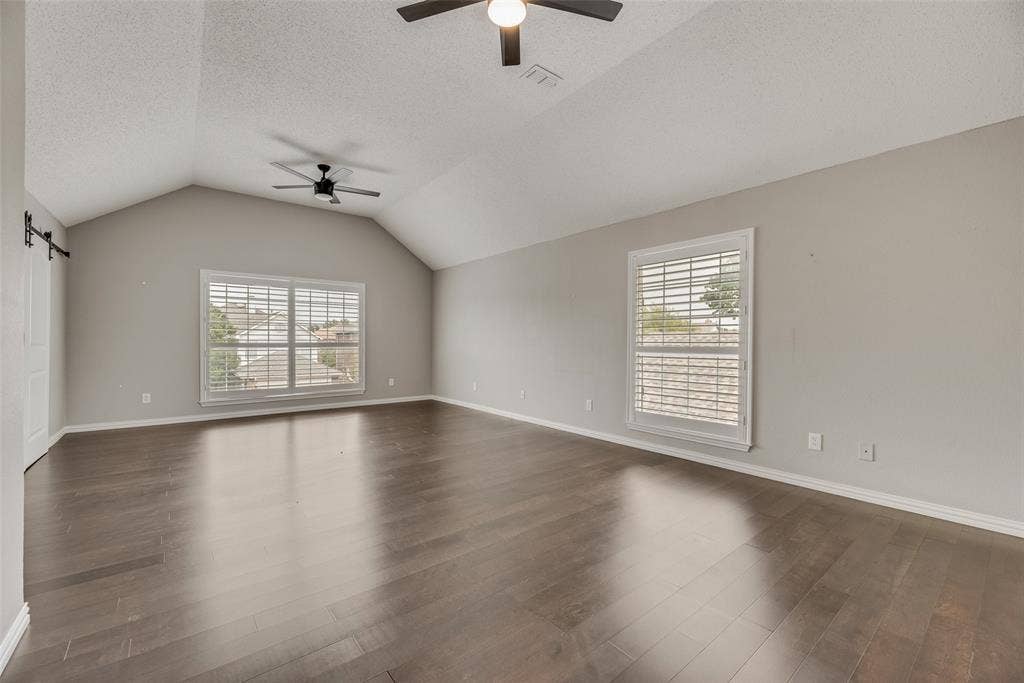 Vaulted ceiling, wood-finish flooring, dual ceiling fans, plantation shutters, and sliding barn door hardware