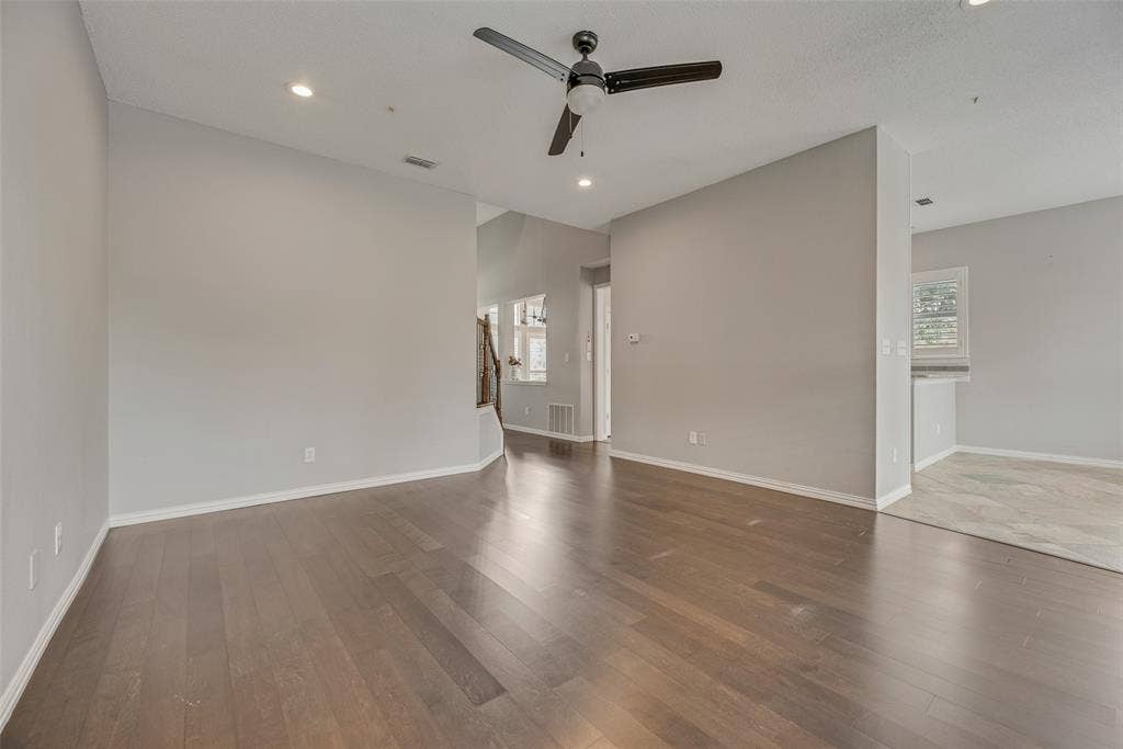Wood-finish flooring throughout the main area, complemented by recessed lighting and a ceiling fan