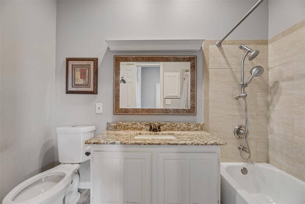 White vanity with a granite-style countertop, undermount sink, and polished chrome faucet