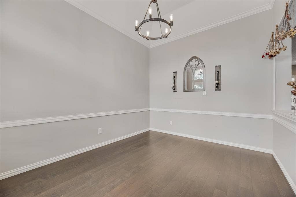 Wood-finish flooring, chair rail molding, crown molding, and an overhead chandelier