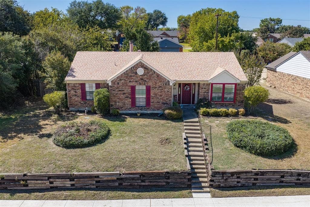 Brick exterior with a shingle roof and decorative shutters