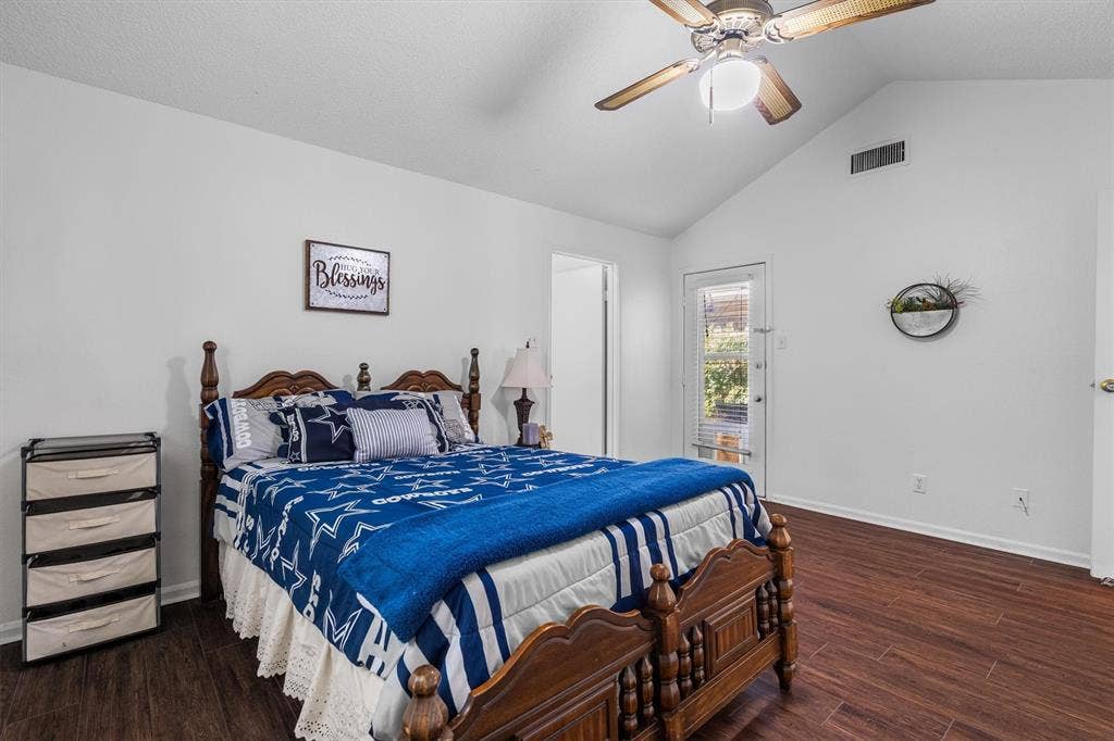 Vaulted ceiling with an attached ceiling fan, wood-finish flooring, and a glass-paneled door