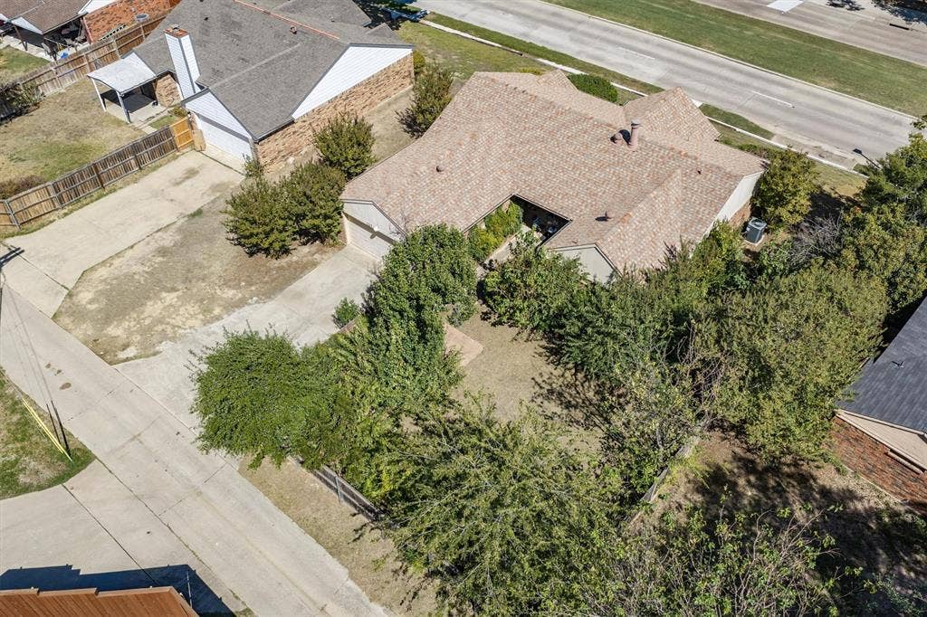 Expansive property featuring a concrete driveway, mature trees, and a shingle roof