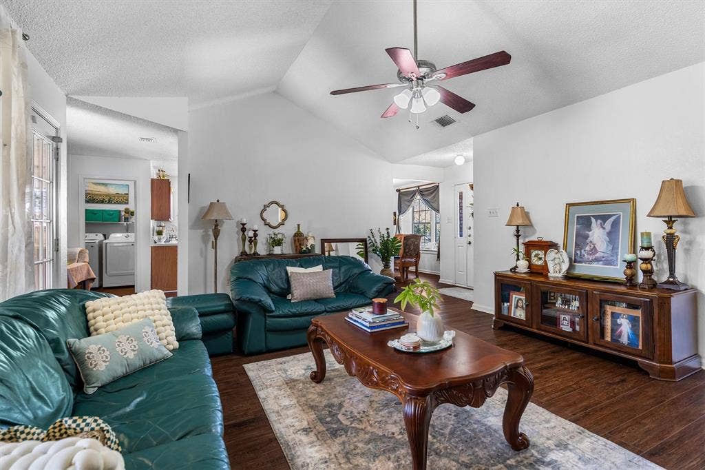 Vaulted ceiling with a ceiling fan, wood-finish flooring, and a glass-paneled door
