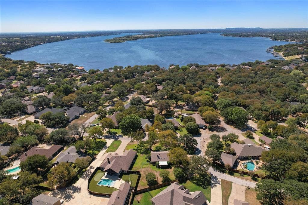 5203 Thunderbird Trail, De Cordova, TX 76049 Aerial perspective showcasing a residential area with a prominent body of water, featuring numerous mature trees throughout the neighborhood