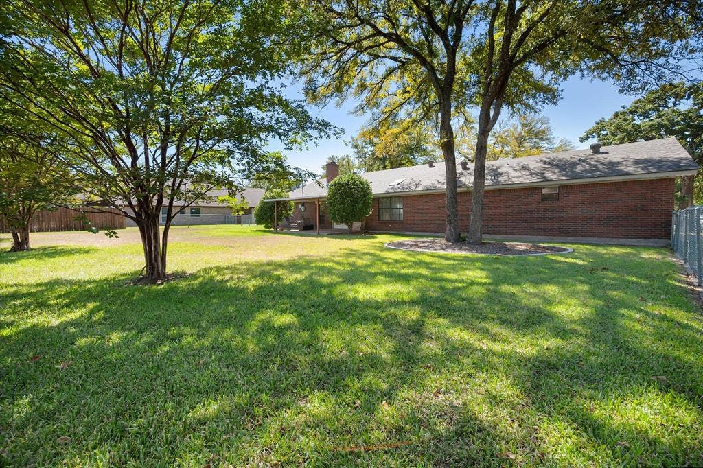 5203 Thunderbird Trail, De Cordova, TX 76049 Expansive backyard featuring mature trees, a manicured lawn, and a brick exterior