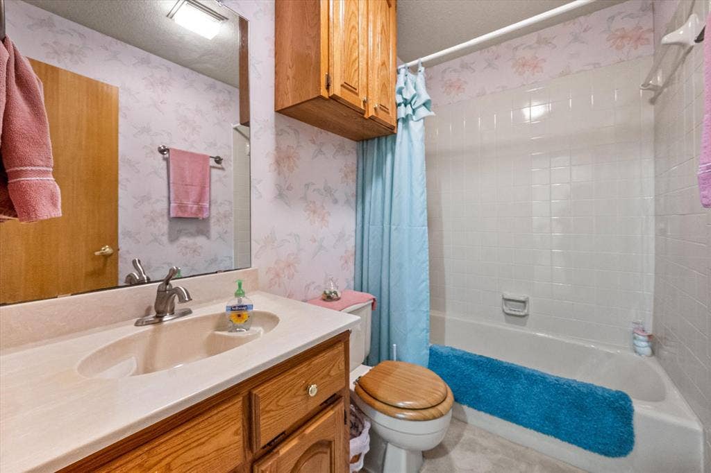 5203 Thunderbird Trail, De Cordova, TX 76049 Bathroom featuring a vanity with a drop-in sink, wood-finish cabinetry, a built-in tub with tile surround, and an overhead lighting fixture