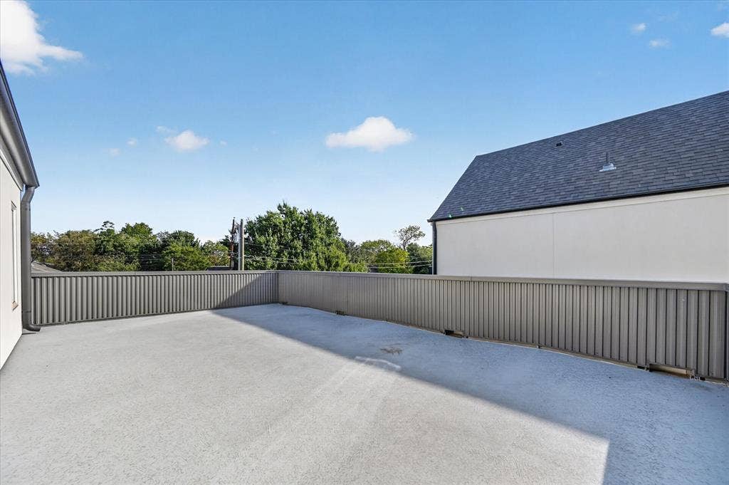 Expansive paved rooftop terrace with a low-profile perimeter fence and durable shingle roofing
