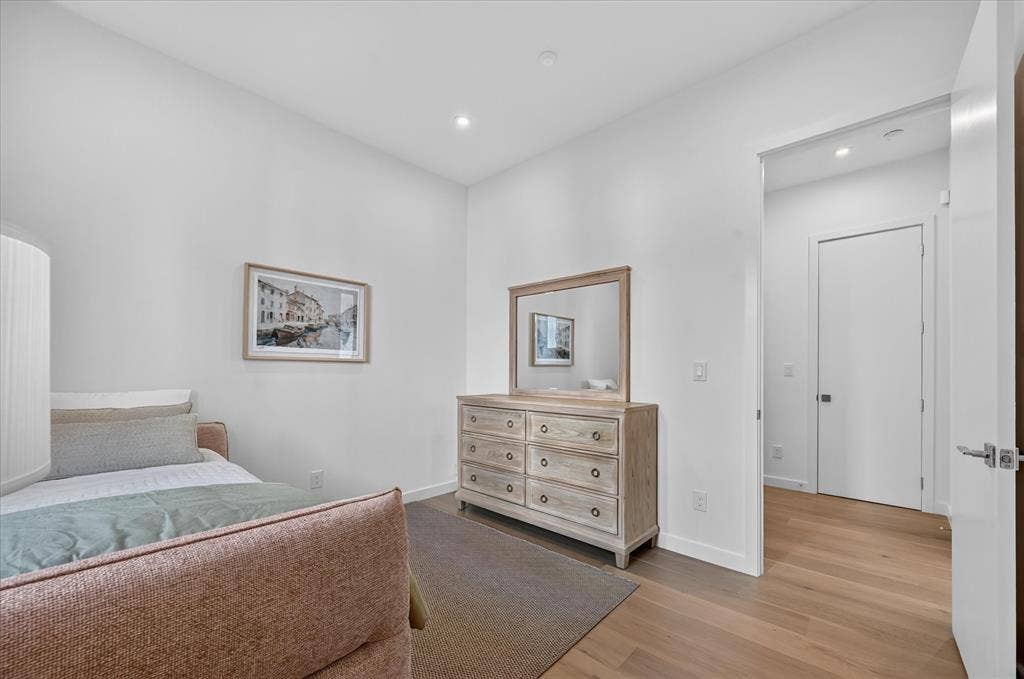Hardwood flooring, recessed lighting, and a white interior door with brushed nickel hardware