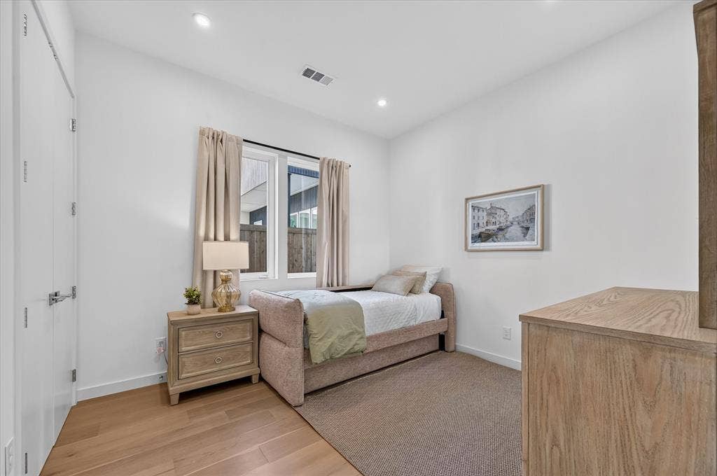 Recessed lighting, wood-finish flooring, and a large window providing natural light
