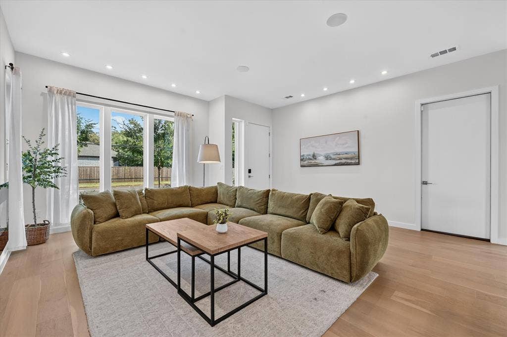 Recessed lighting, light wood-finish flooring, white walls, and a large window
