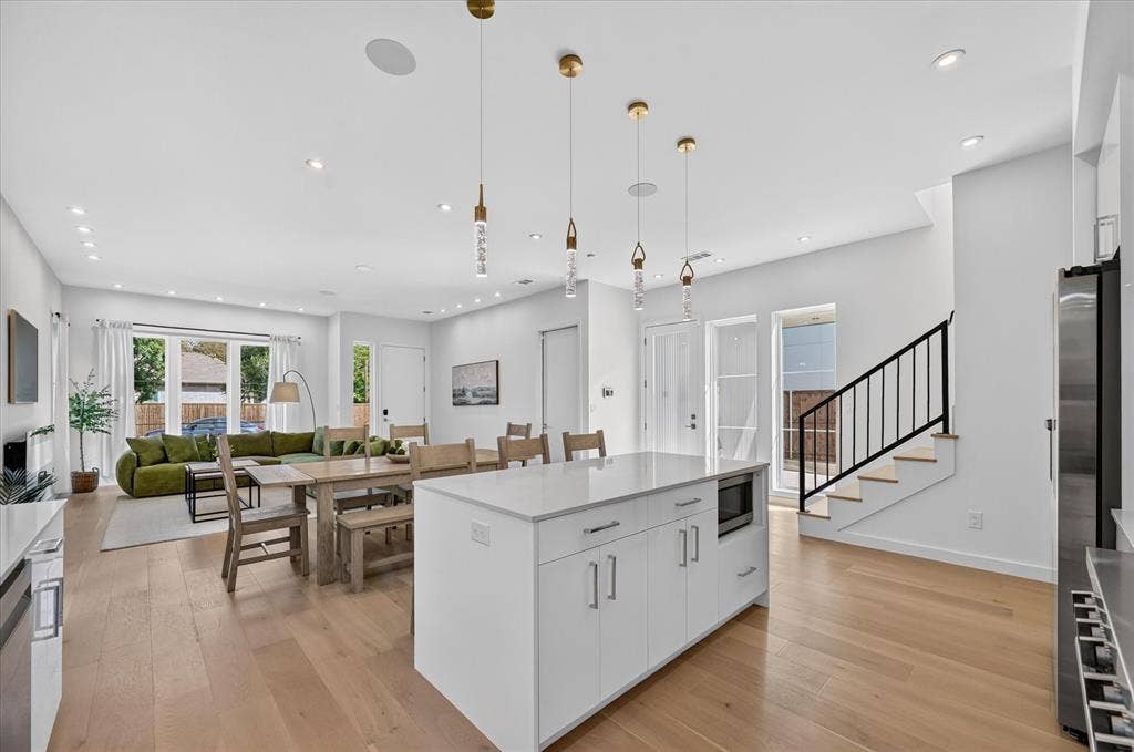 Open-concept living area with light wood-finish flooring, recessed lighting, and a kitchen island featuring a light-toned countertop