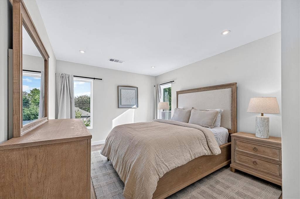 Recessed lighting, light-toned walls, wood-finish flooring, and multiple windows with outdoor scenery