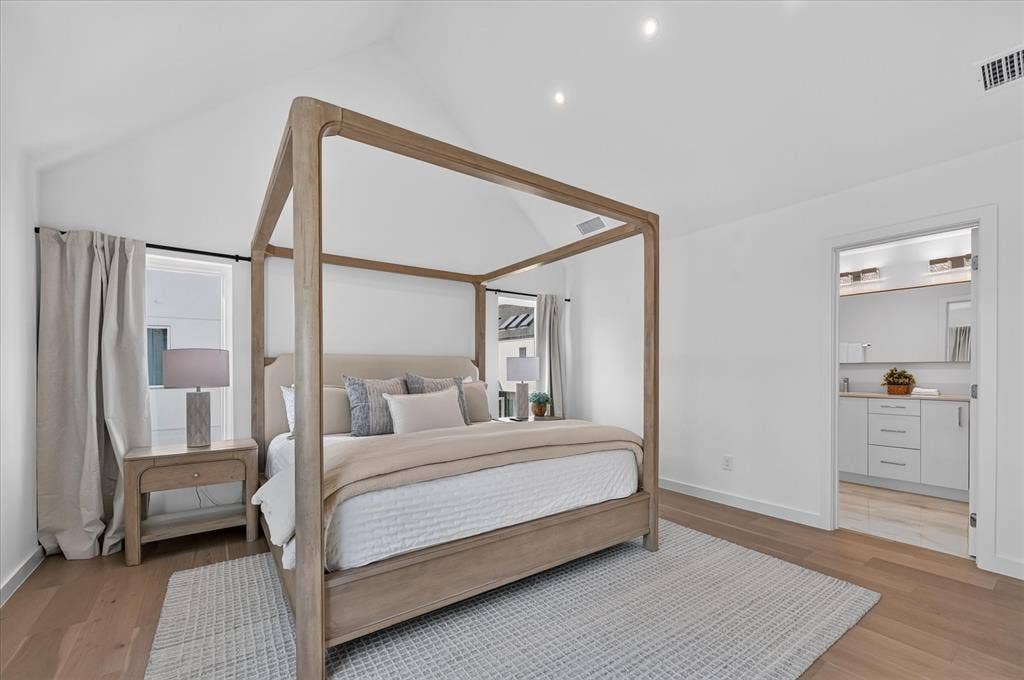 Vaulted ceiling with recessed lighting, light wood-finish flooring, and white walls