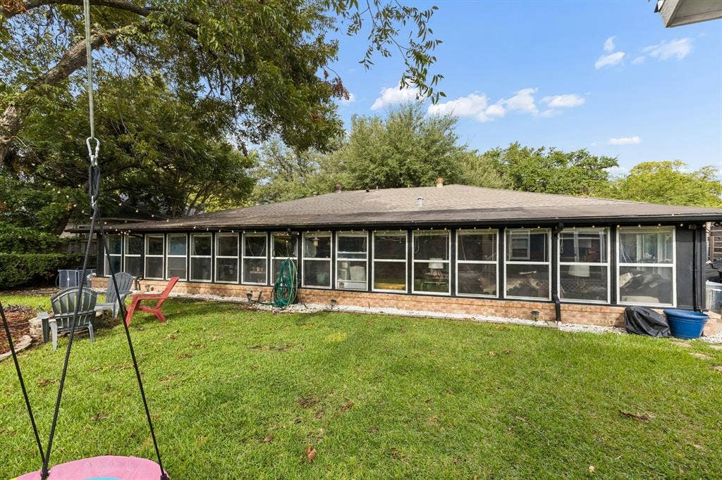 7230 Edgerton Drive, Dallas, TX 75231 Brick exterior featuring an expansive wall of windows, a hipped roofline, and a mature tree-lined backyard