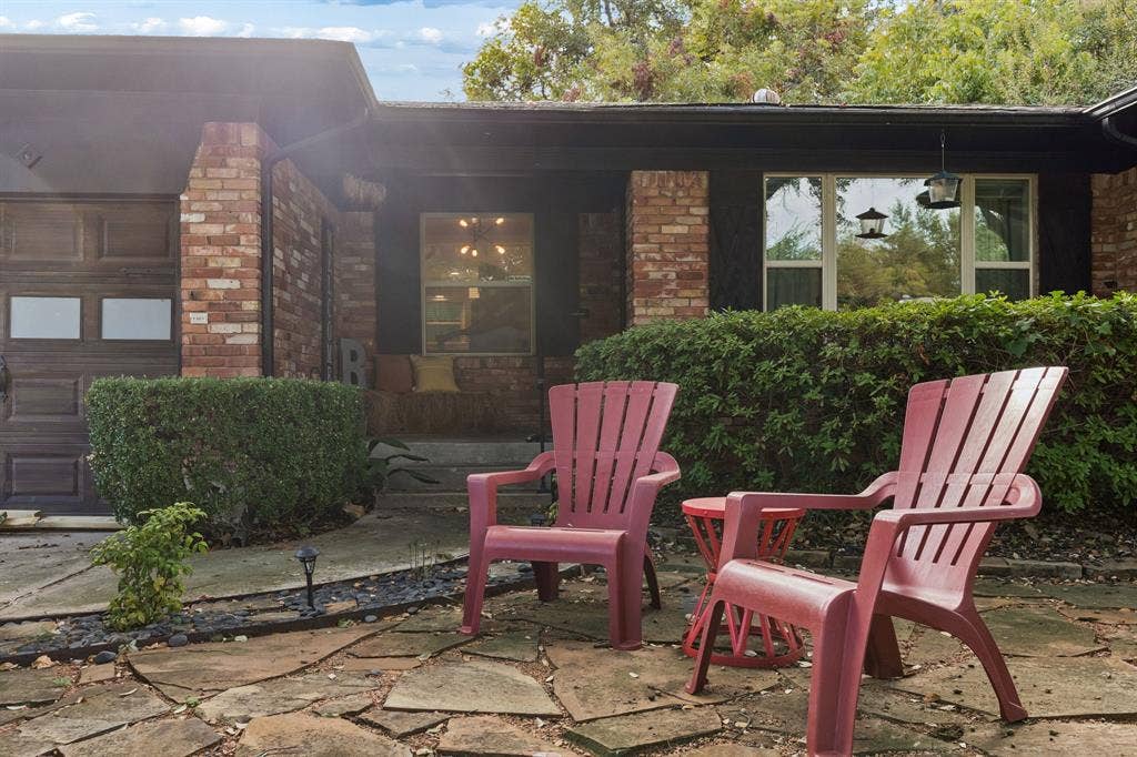 7230 Edgerton Drive, Dallas, TX 75231 Exterior facade featuring a combination of red brick masonry and dark trim, flagstone patio, and integrated garage with frosted glass panels
