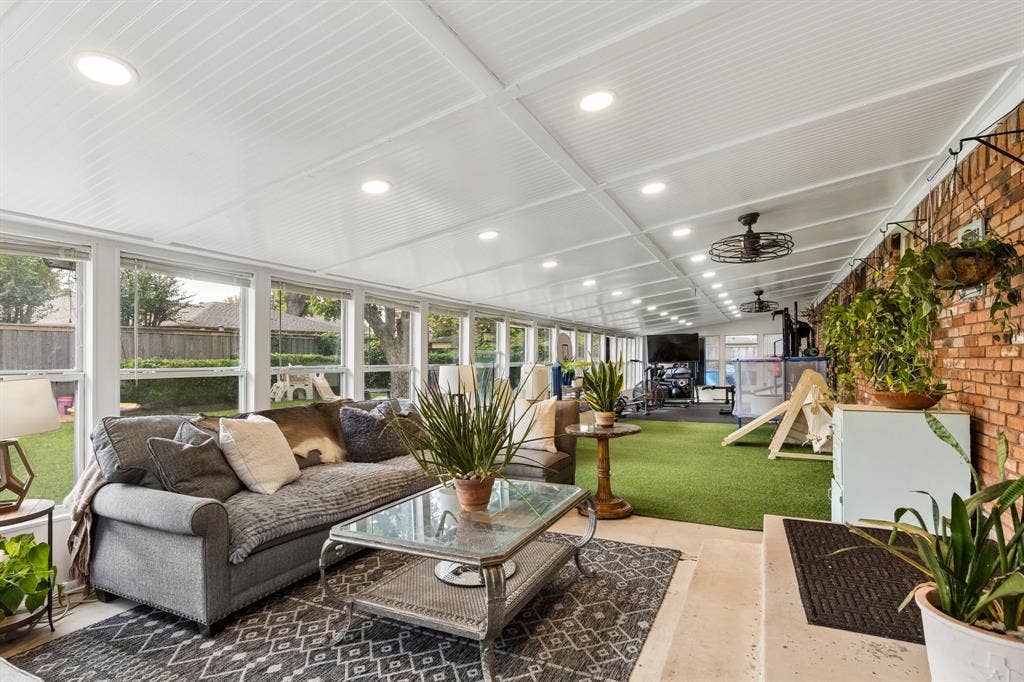 7230 Edgerton Drive, Dallas, TX 75231 Enclosed patio featuring extensive window walls, a beadboard ceiling with recessed lighting, an exposed brick wall, and artificial turf flooring
