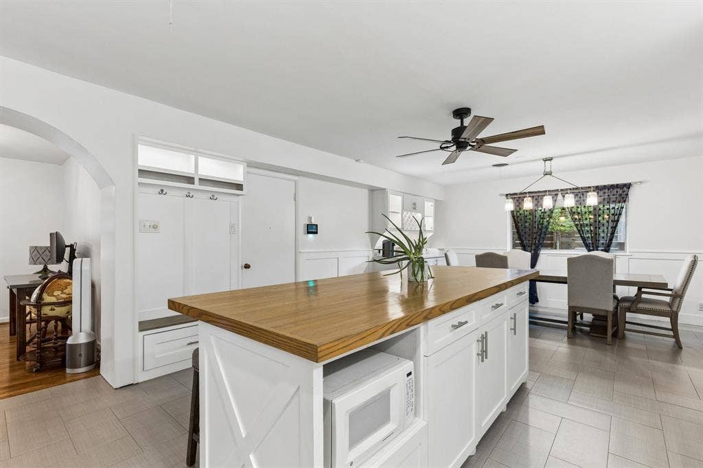 7230 Edgerton Drive, Dallas, TX 75231 Center island featuring a wood-finish countertop and built-in microwave, integrated mudroom storage cabinetry, ceiling-mounted fan, tile flooring, and wall paneling