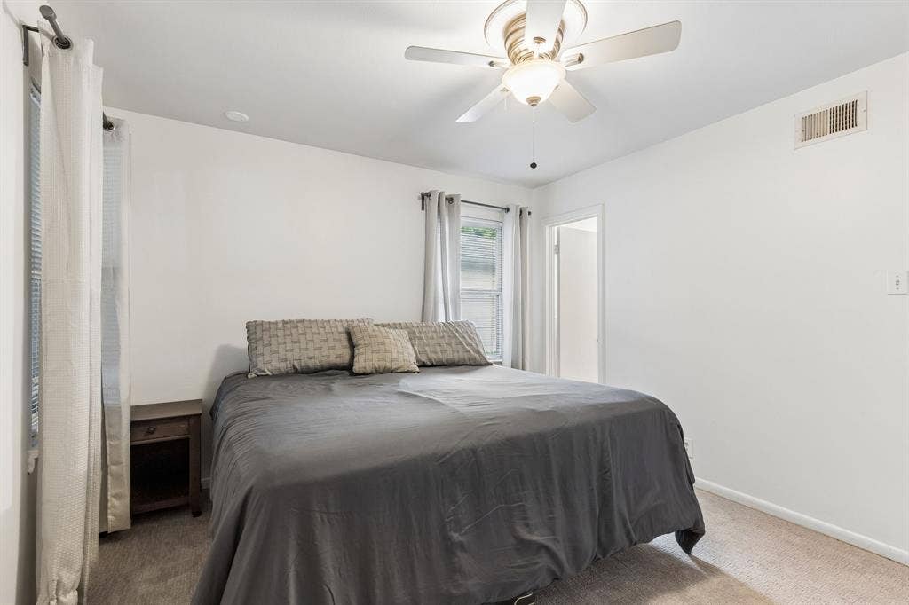7230 Edgerton Drive, Dallas, TX 75231 Neutral-toned interior space featuring wall-to-wall carpeting, multiple windows, and a ceiling-mounted light fixture with a five-blade fan