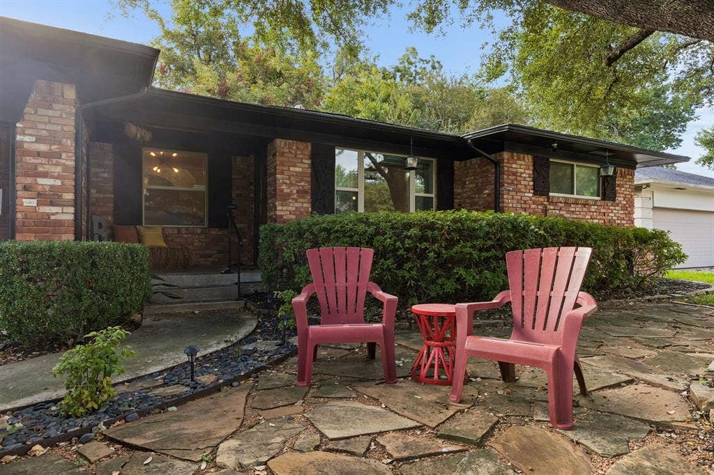 7230 Edgerton Drive, Dallas, TX 75231 Single-story brick exterior featuring a flagstone patio, mature landscaping, and multi-pane windows