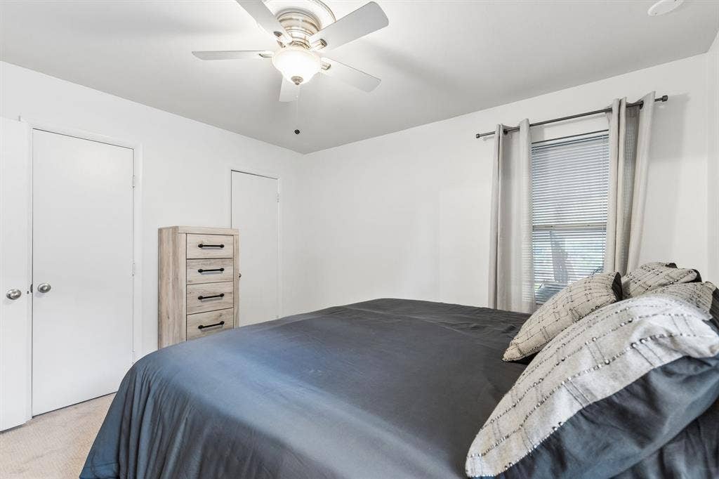 7230 Edgerton Drive, Dallas, TX 75231 Neutral-toned carpet, white walls, ceiling fan with integrated lighting, and dual-door closet