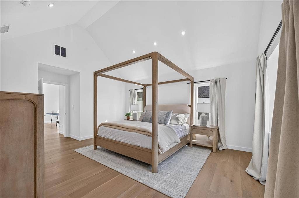 835 Nomas Street, Dallas, TX 75212 Bright primary bedroom showcasing a four-poster canopy bed frame in natural wood, wide-plank wood-finish flooring throughout, recessed ceiling lighting, and a neutral color palette with soft furnishings
