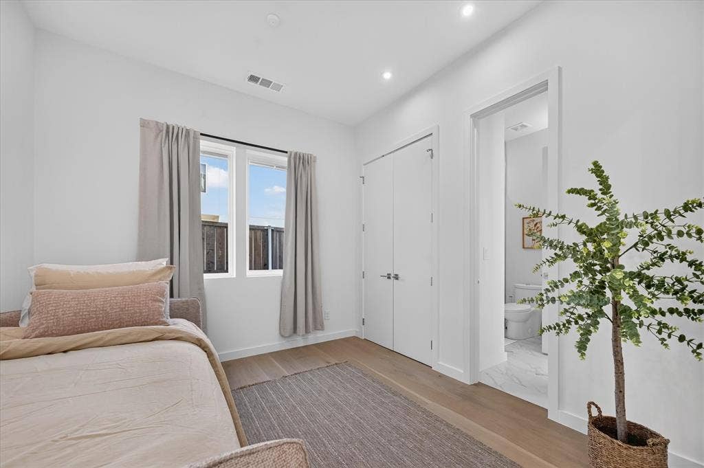 835 Nomas Street, Dallas, TX 75212 Bright secondary bedroom featuring hardwood flooring, floor-to-ceiling white closet doors, and glass-paneled French doors with thermal-pane windows