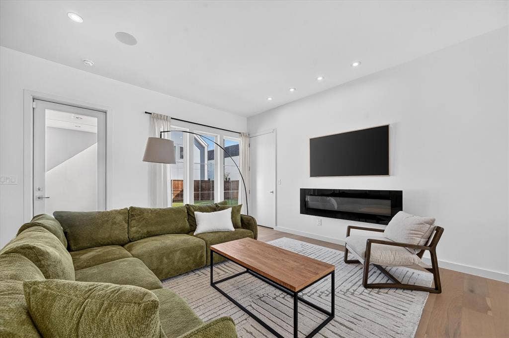 835 Nomas Street, Dallas, TX 75212 Modern living room featuring a curved olive-toned sectional sofa, wood-finish flooring, and neutral wall finishes