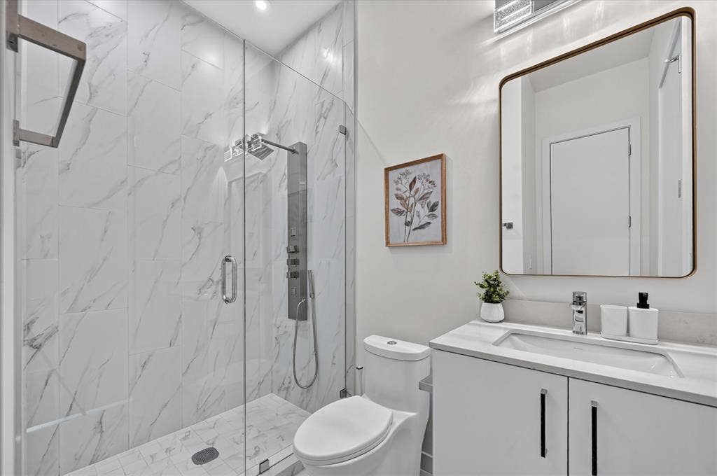 835 Nomas Street, Dallas, TX 75212 Glass-enclosed shower with a multi-function shower panel, white marble-look tile walls, and a matching tile shower pan
