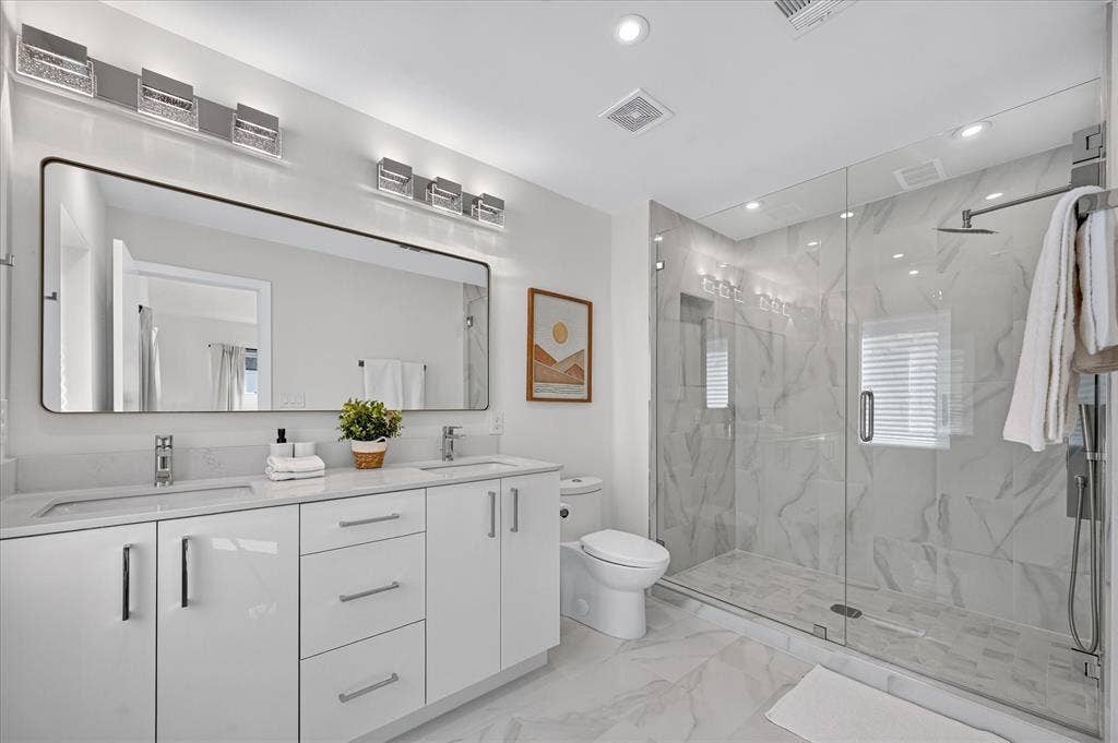 835 Nomas Street, Dallas, TX 75212 Dual vanity with white cabinetry, stone countertops, and polished chrome fixtures