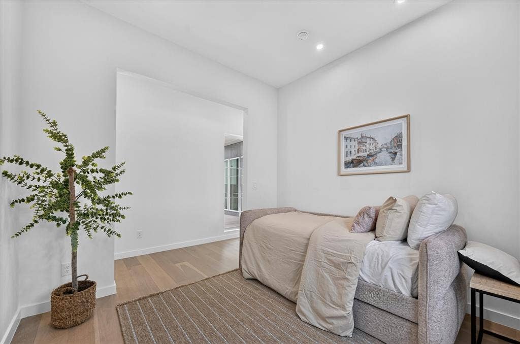 835 Nomas Street, Dallas, TX 75212 Bright secondary bedroom featuring wood-finish flooring, recessed ceiling lighting, and abundant natural light from the entry passage