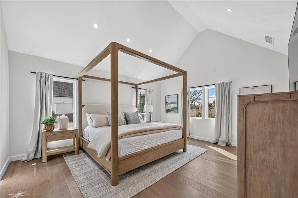 835 Nomas Street, Dallas, TX 75212 Primary Bedroom Suite featuring a wood-frame four-poster bed, hardwood flooring, vaulted ceiling with recessed lighting, and dual glass doors opening to natural light