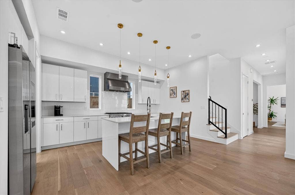 835 Nomas Street, Dallas, TX 75212 Gourmet kitchen with stainless steel appliances, white cabinetry, a center island, and pendant lighting