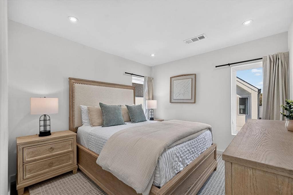 835 Nomas Street, Dallas, TX 75212 Primary bedroom featuring a wood-frame bed with nailhead trim, coordinating wood nightstands with drawer storage, recessed ceiling lighting, and large windows with neutral drapery