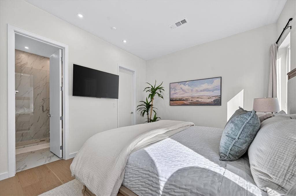 835 Nomas Street, Dallas, TX 75212 Light wood-finish flooring, recessed lighting, wall-mounted television, and a bathroom entry with full tile walls and glass shower enclosure