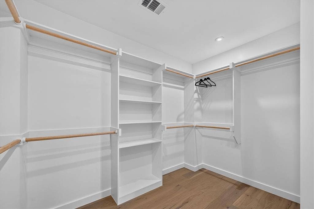 835 Nomas Street, Dallas, TX 75212 Spacious walk-in closet featuring custom built-in shelving and double hanging rods with wood-finish trim accents