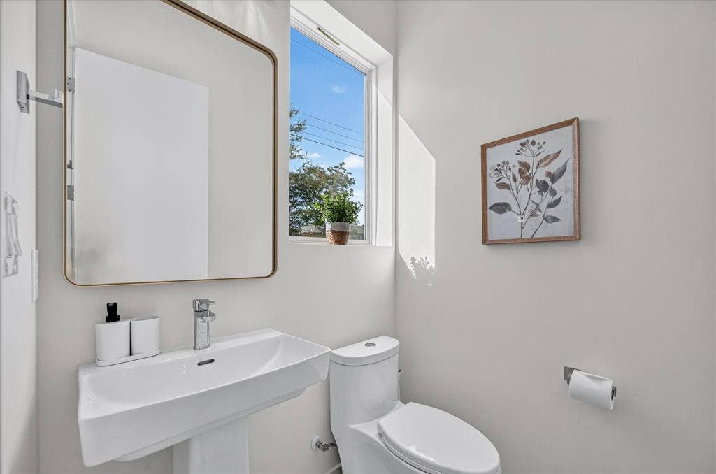 835 Nomas Street, Dallas, TX 75212 Modern powder room featuring a floating white vanity with an integrated rectangular sink, chrome wall-mounted faucet, and polished countertop