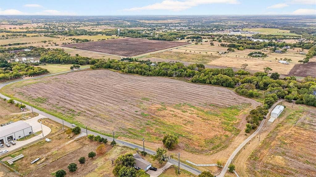 Expansive acreage featuring cleared open land, mature tree lines, and paved road frontage