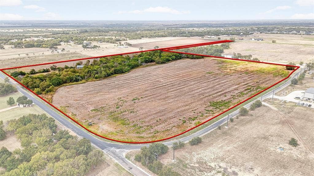 Expansive acreage featuring cleared land, mature tree clusters, and dual-road frontage