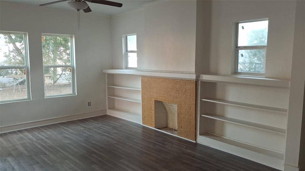 1224 Frost Avenue, Waco, TX 76708 Wood-finish flooring, built-in shelving, textured fireplace surround, ceiling fan, and multiple windows