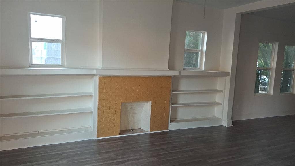 1224 Frost Avenue, Waco, TX 76708 Built-in shelving flanking a textured fireplace surround, with multiple windows and wood-finish flooring