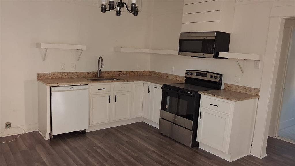 1224 Frost Avenue, Waco, TX 76708 White cabinetry with black hardware, stone-finish countertops, stainless steel appliances, wood-finish flooring, and a decorative light fixture