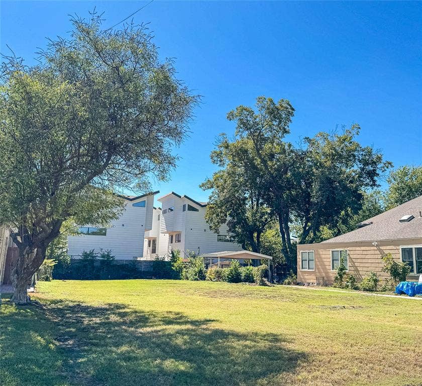 5946 Lewis Street, Dallas, TX 75206 Expansive green lawn with mature trees and a modern-style residence featuring white siding and angular rooflines
